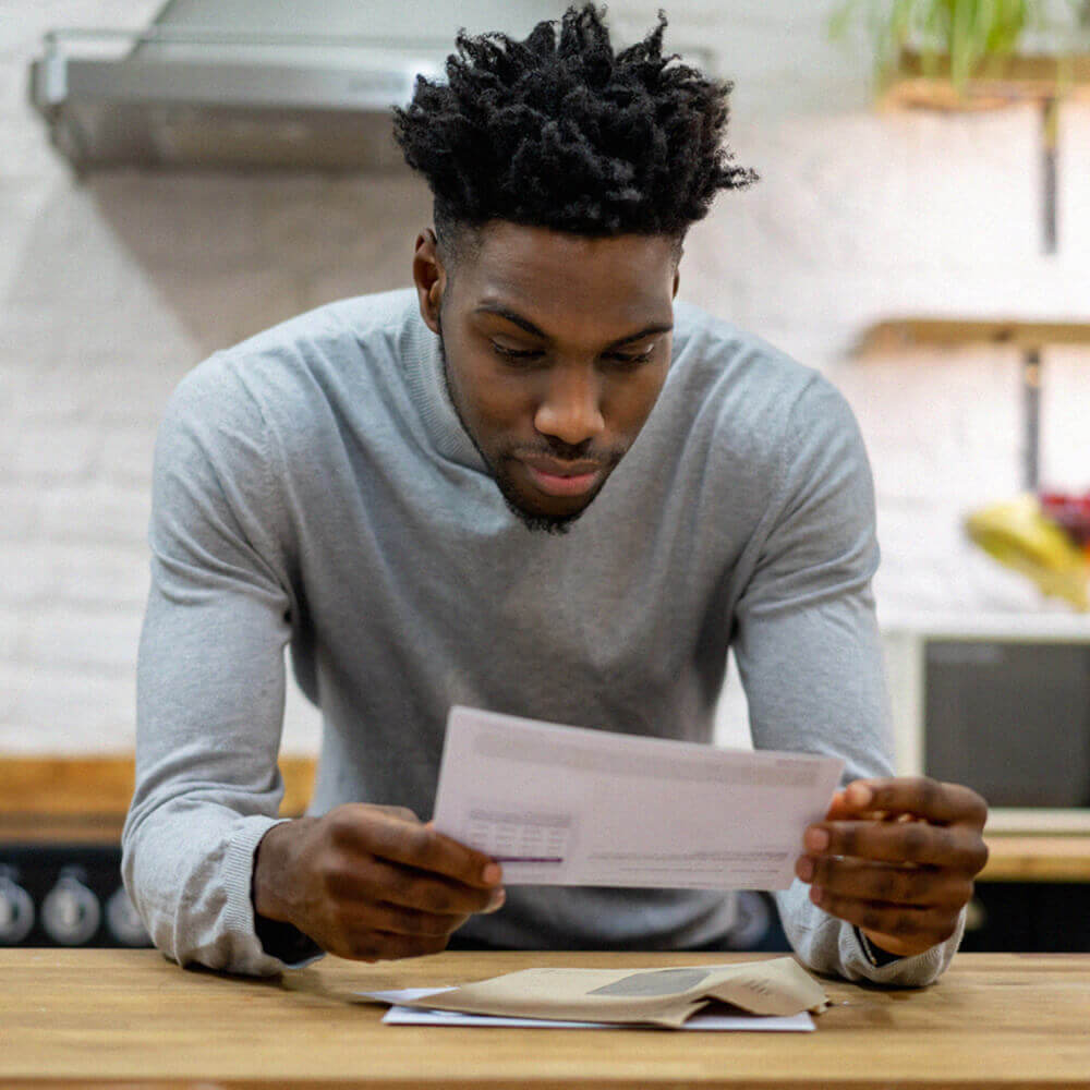 man leaning on counter reading letter
