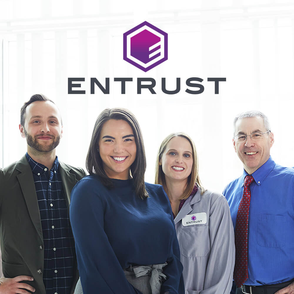 group of employees in front of entrust logo