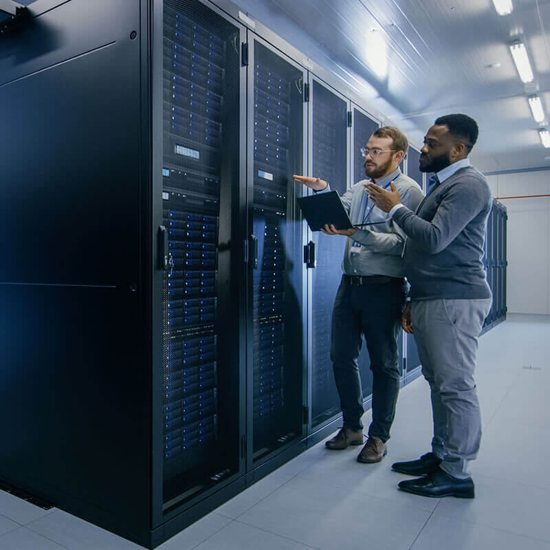 two men standing in server room and pointing at server