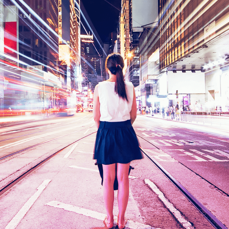 woman standing on street of blurred city at night