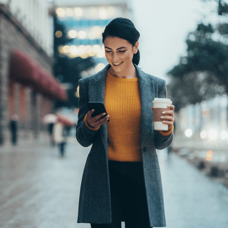 Woman holding coffee and using a phone