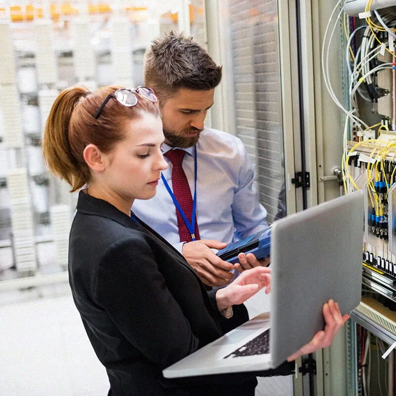 man and woman on laptop on server room
